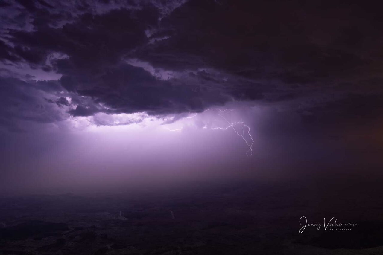 Nachtszene mit einem dramatischen Blitz, der den Himmel über einer ländlichen Landschaft erleuchtet.